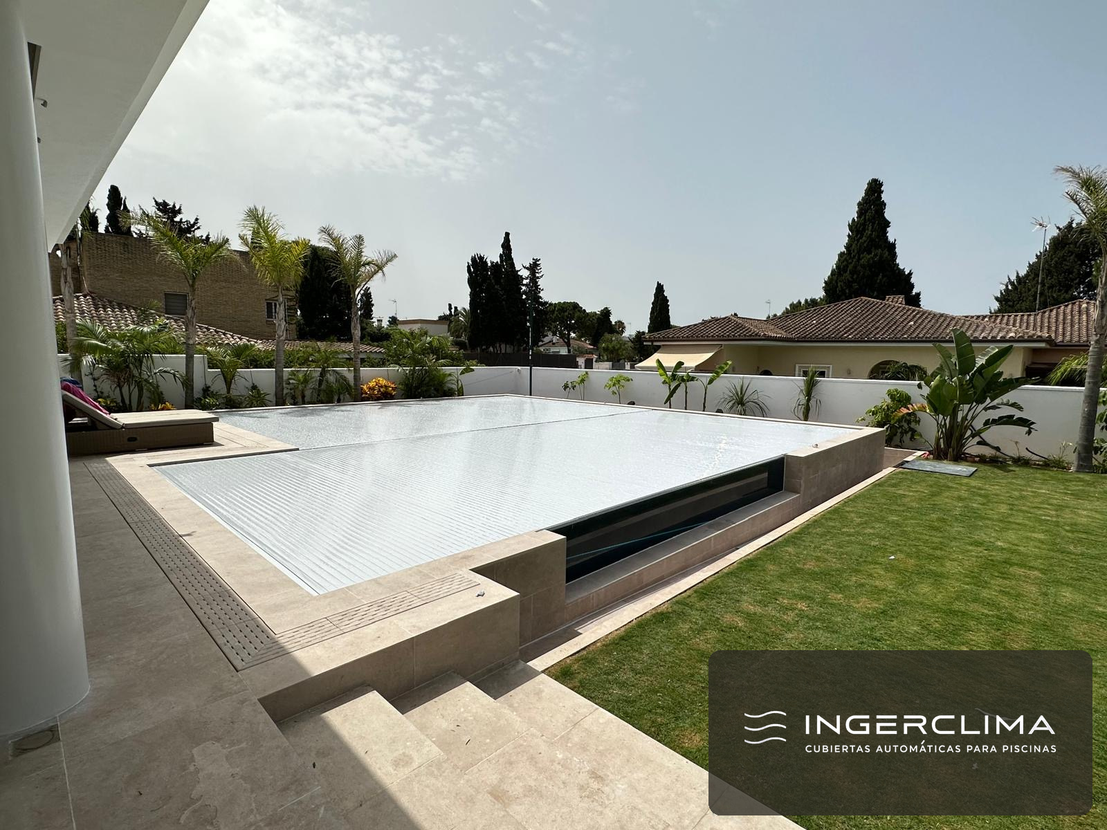 White cover closed over a raised pool, with a hedge behind