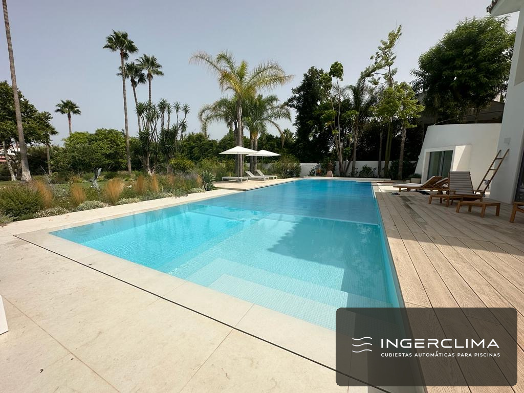 Clear polycarbonate slatted cover closed over a garden pool, with the water visible through the slats
