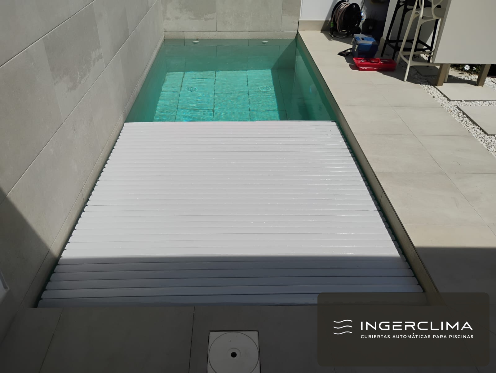 White slatted cover half open over a courtyard pool