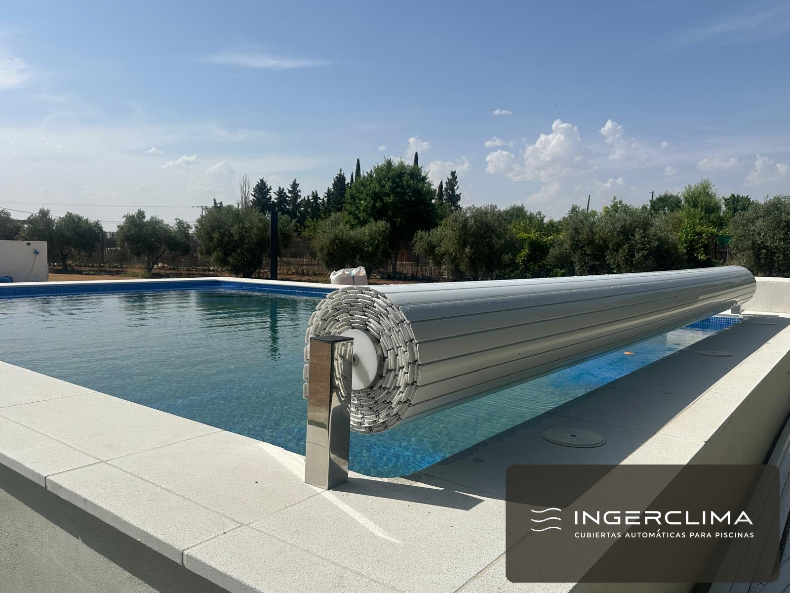 Grey cover rolling onto its shaft, with olive trees behind