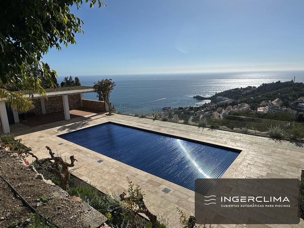 Blue slatted cover closed over a pool with sea views