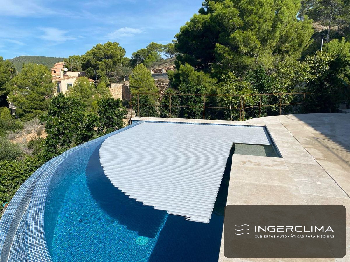 Cubierta automática de lamas cerrada sobre la piscina del jardín común de un edificio de viviendas