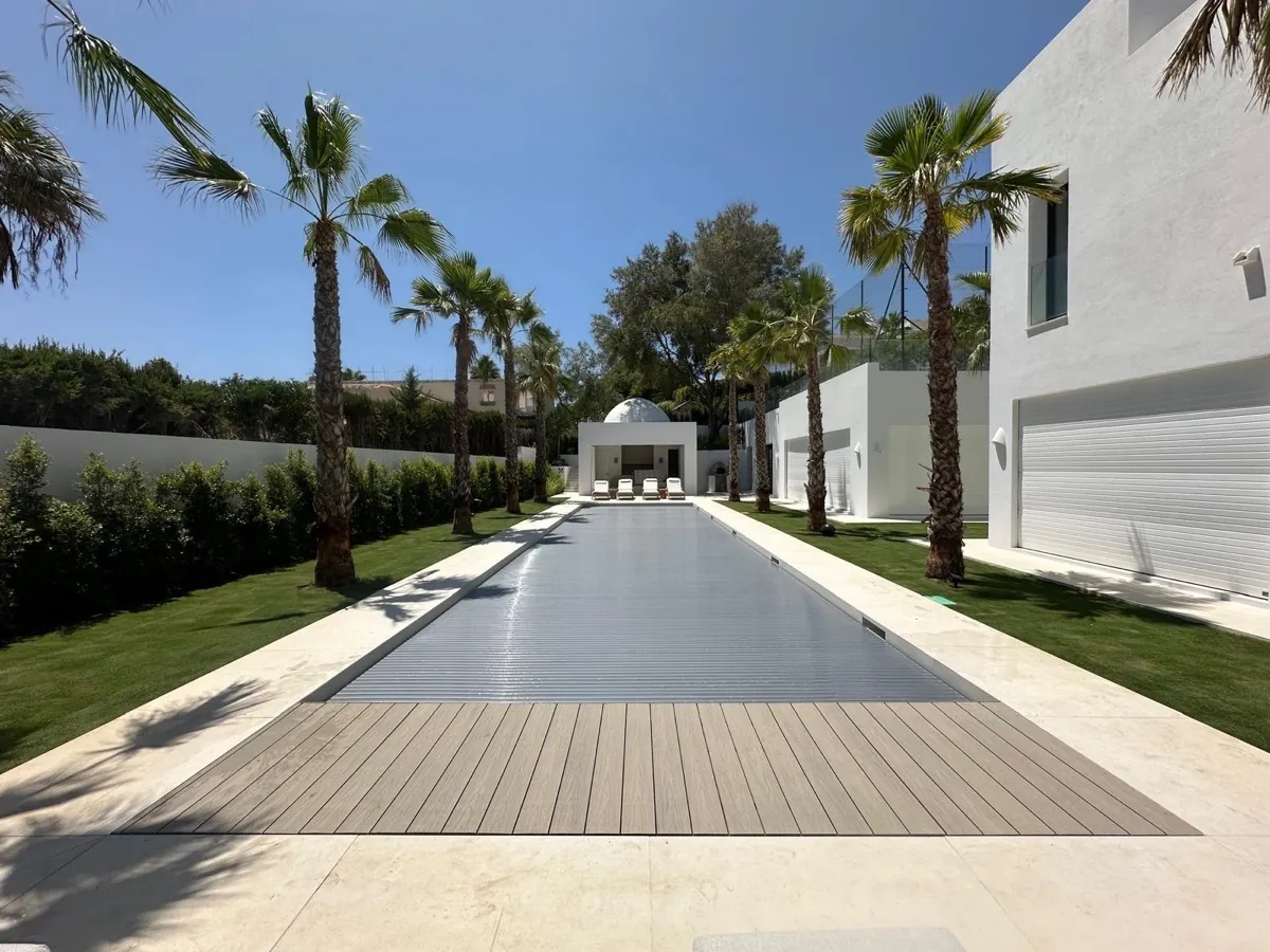 Piscina de lámina de agua alargada cubierta con lama de policarbonato solar platinum en una villa moderna de Sotogrande, Cádiz, instalada por Ingerclima